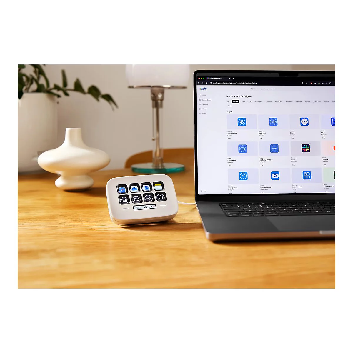 Ein weißes Stream Deck neben einem Laptop. Auf dem Laptop-Bildschirm sind Plugins für Elgato zu sehen.