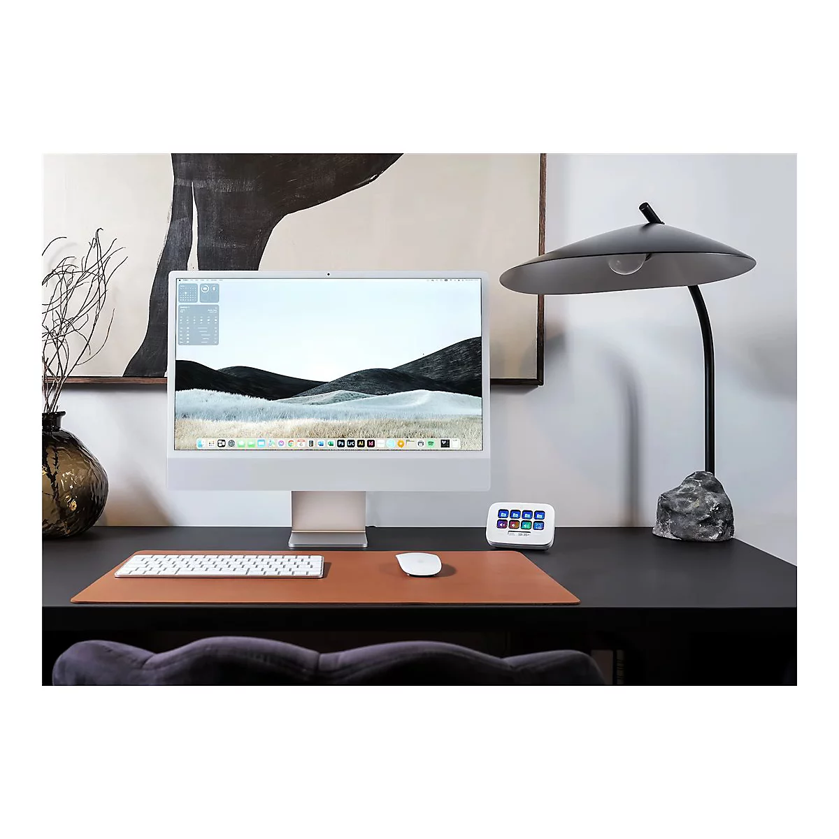 Ein moderner Schreibtisch mit iMac, Tastatur, Maus, Lampe und Dekor.