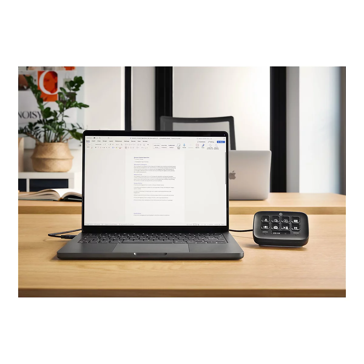 Ein schwarzer Laptop mit geöffnetem Dokument auf einem Holztisch, daneben ein Stream Deck.