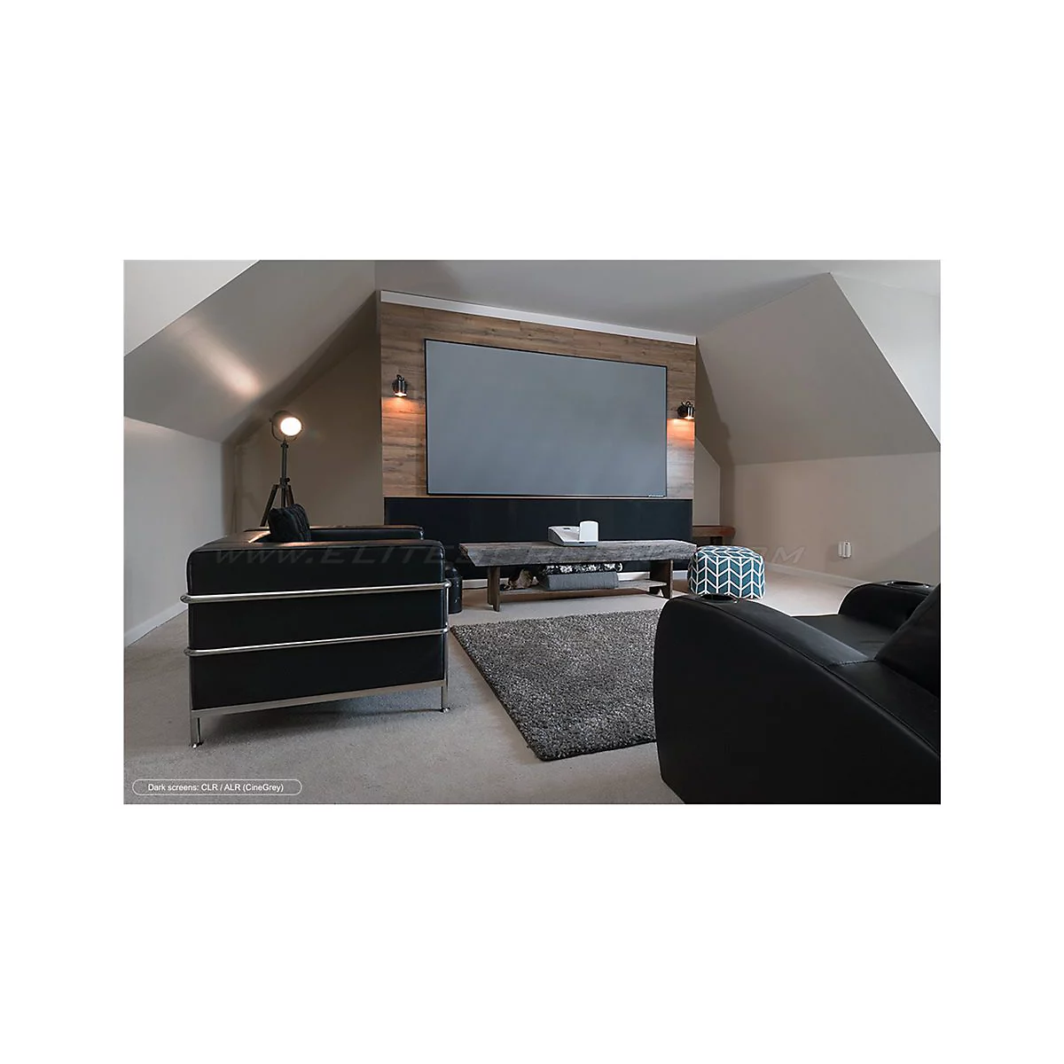 Ein Wohnzimmer mit einem groÃŸen grauen Bildschirm, schwarzen Ledersofas und Holzakzenten. Ein Teppich liegt vor einem niedrigen Tisch.