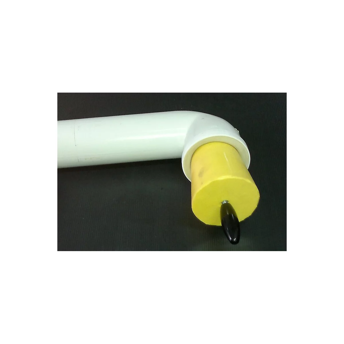 Yellow cylinder with black handle in white elbow. Black background.