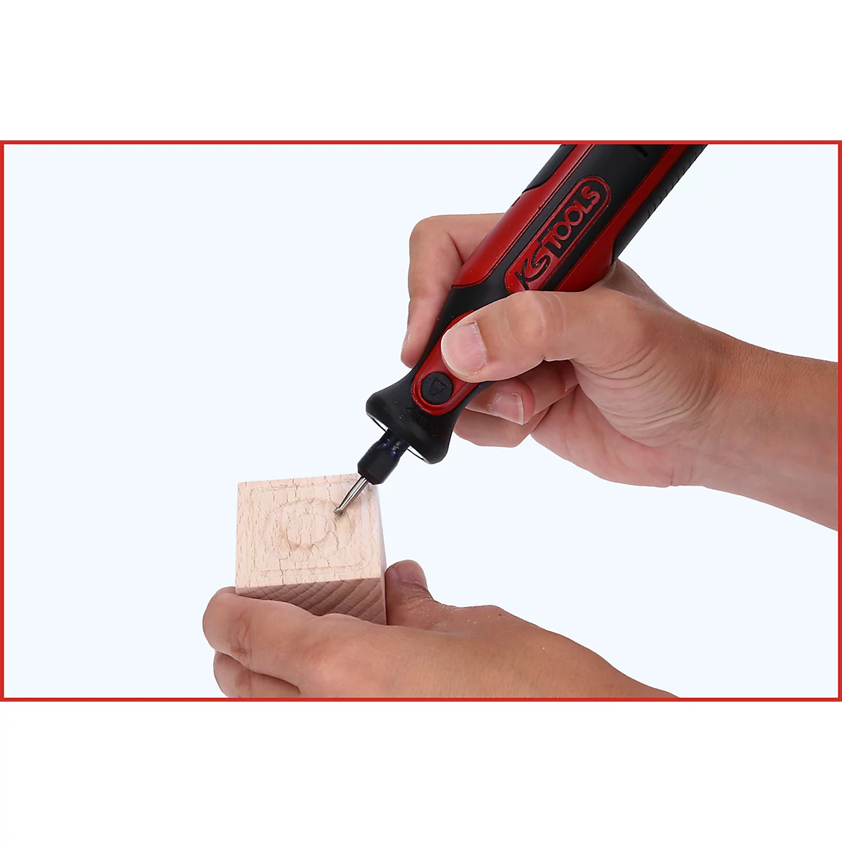 Hand hält rotes und schwarzes Werkzeug, das in Holz schnitzt. Auf dem Werkzeug steht "KS TOOLS".
