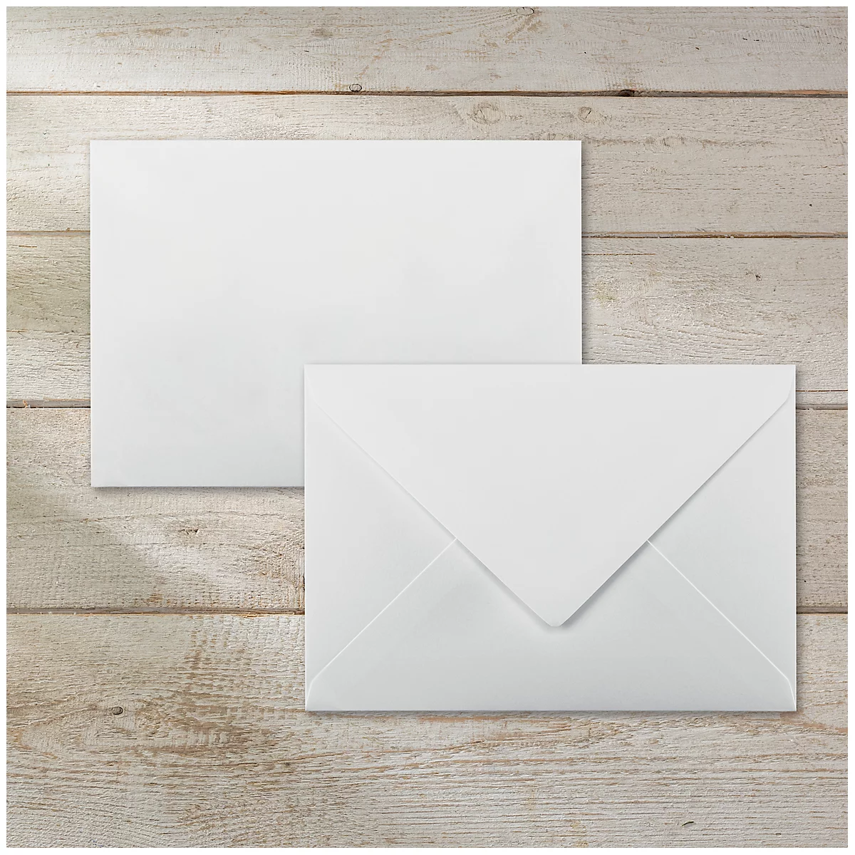 Two white envelopes on a light wooden surface. One is open, the other is closed.