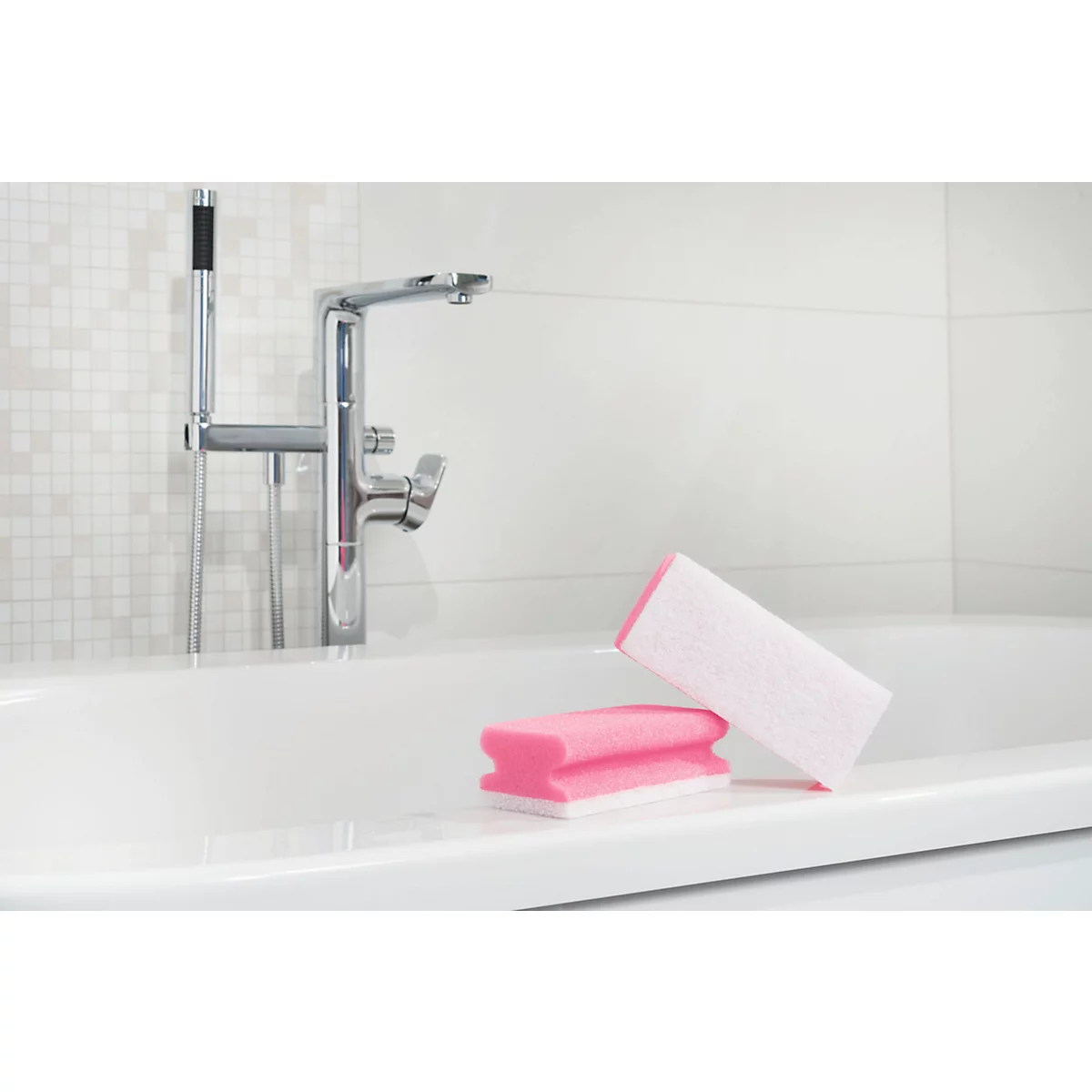 Deux éponges roses et blanches reposent sur le bord d'une baignoire blanche. À l'arrière-plan, un robinet chromé.