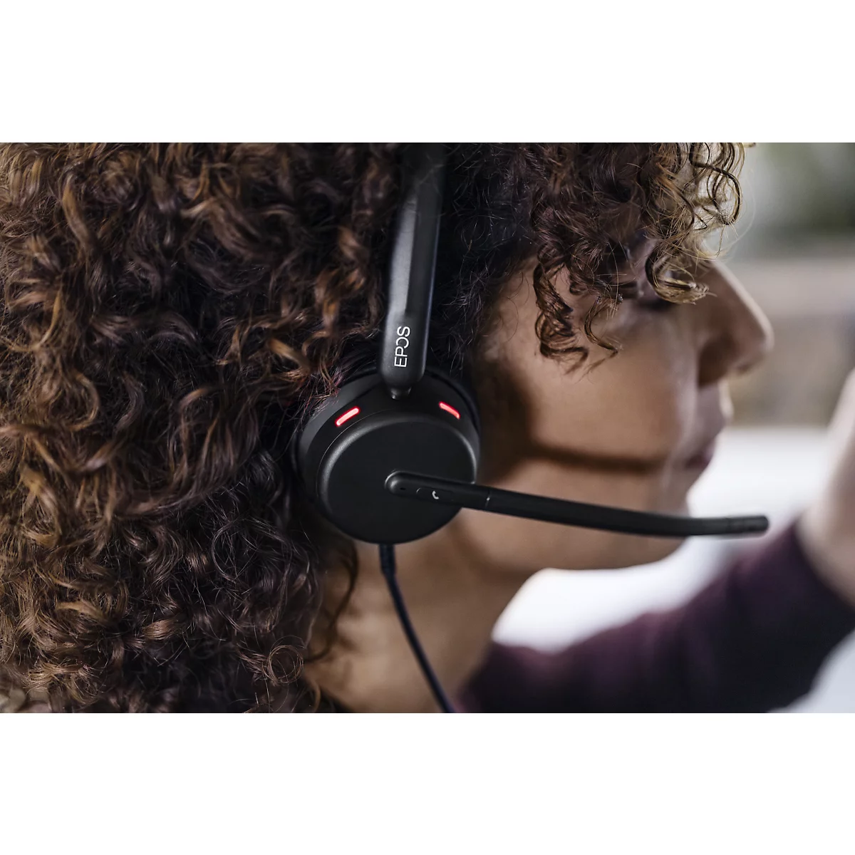 Close-up of a headset with a microphone on a person's head. The device is black, the microphone has a curved shape.