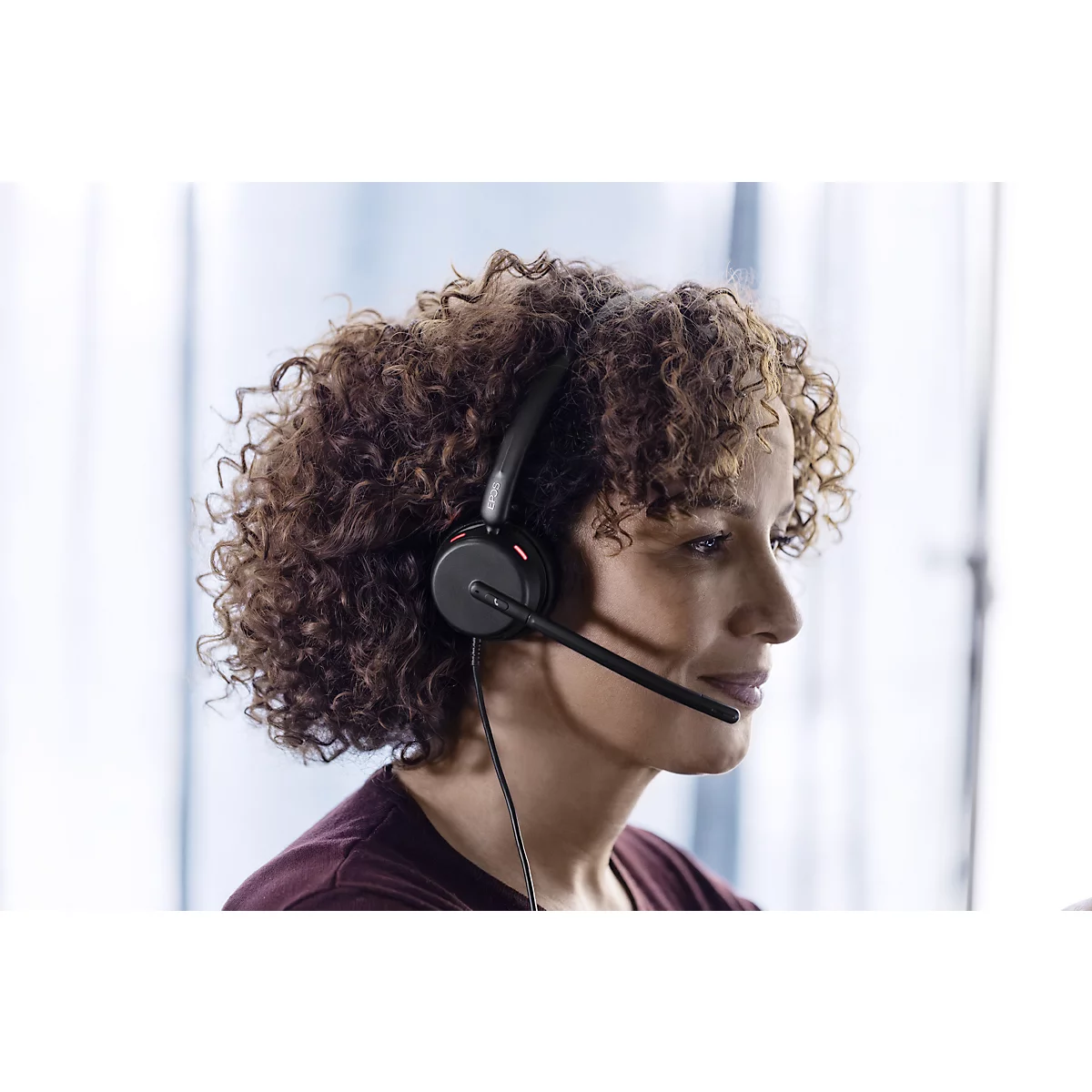 Woman with curly hair wearing a black headset.