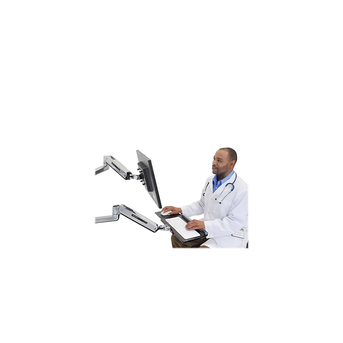 Ein Arzt sitzt vor einem Computer, der auf einem Monitorarm befestigt ist. Der Monitor und die Tastatur sind auf Arme montiert, die es dem Arzt ermÃ¶glichen, die HÃ¶he und Position anzupassen.