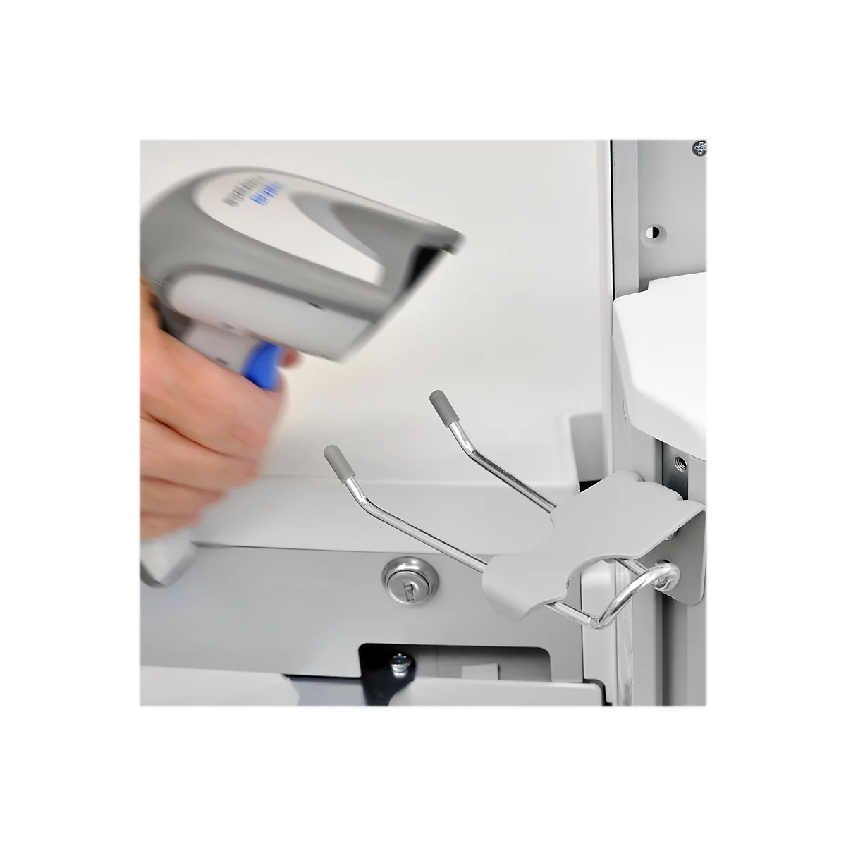 Nahaufnahme: Person scannt mit grauen Barcode-Scanner einen Halter für Hygieneartikel. Graue Metallhalterung und Halterung für Scanner sind im Fokus.