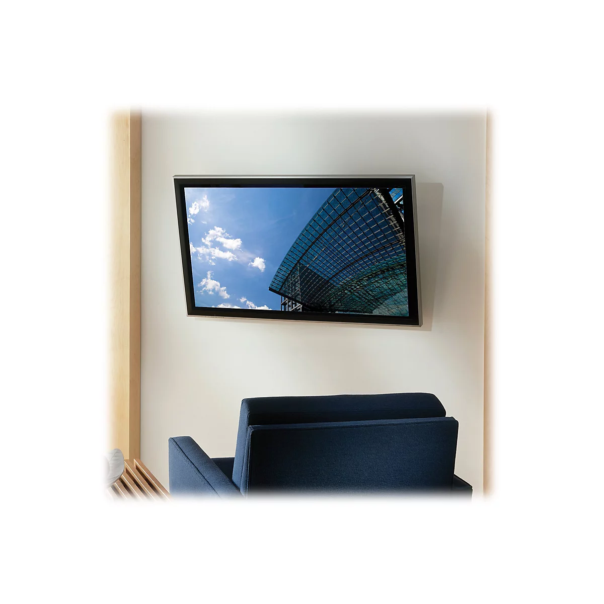 Ein Flachbildfernseher hängt an einer weißen Wand über einem blauen Sessel.