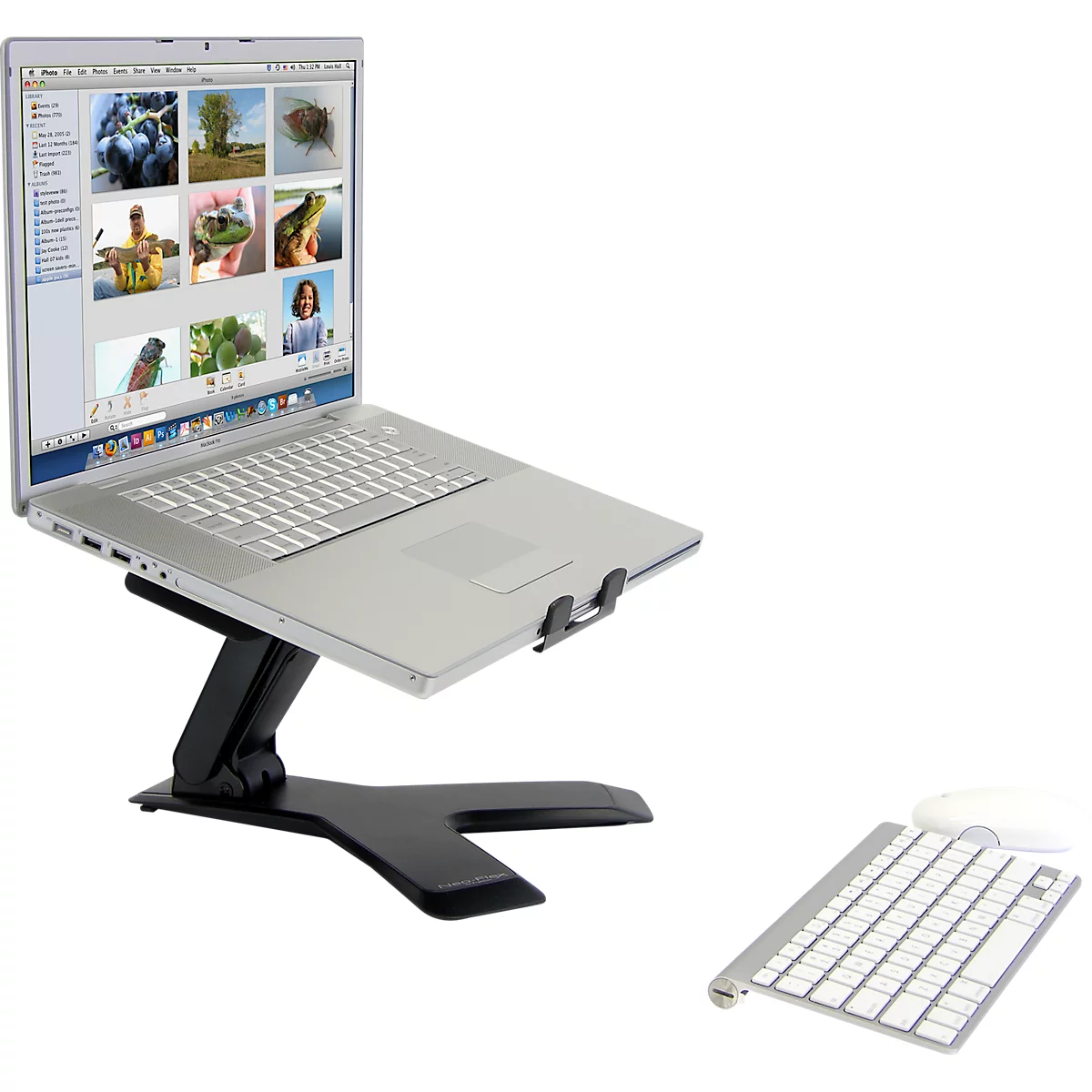 Ein Laptop steht auf einem schwarzen Ständer, daneben Tastatur und Maus. Der Laptop zeigt Bilder an.