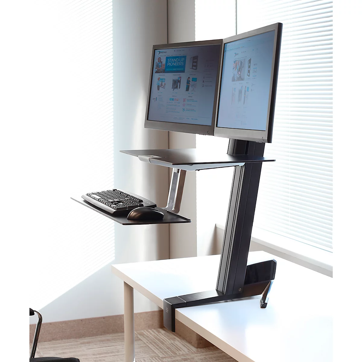 Black height-adjustable desk with two monitors, keyboard and mouse.