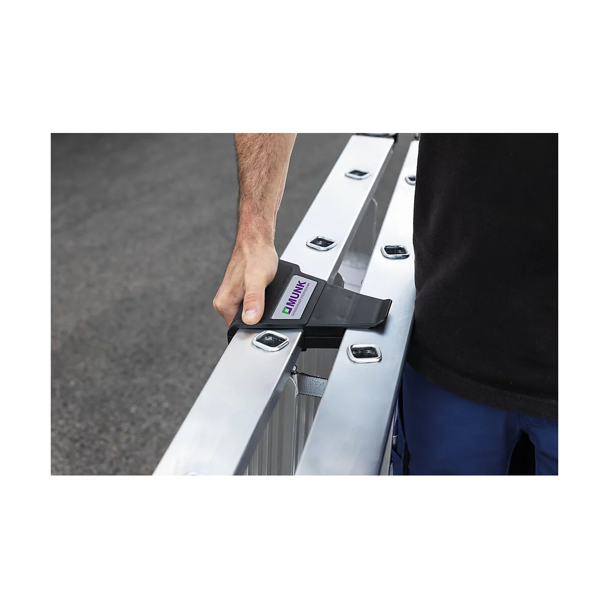 Un homme tient l'échelle d'une main. Il y a le mot "MUNK" en violet sur le support.