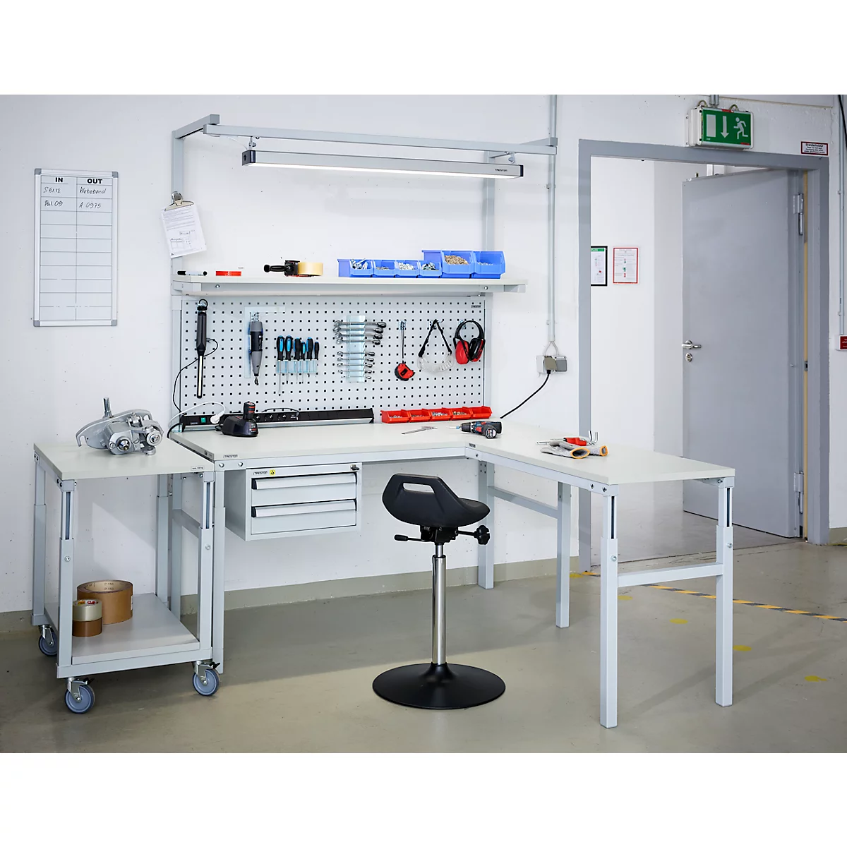 Workbench with tools. On the wall a pegboard with tools, a whiteboard on the left.