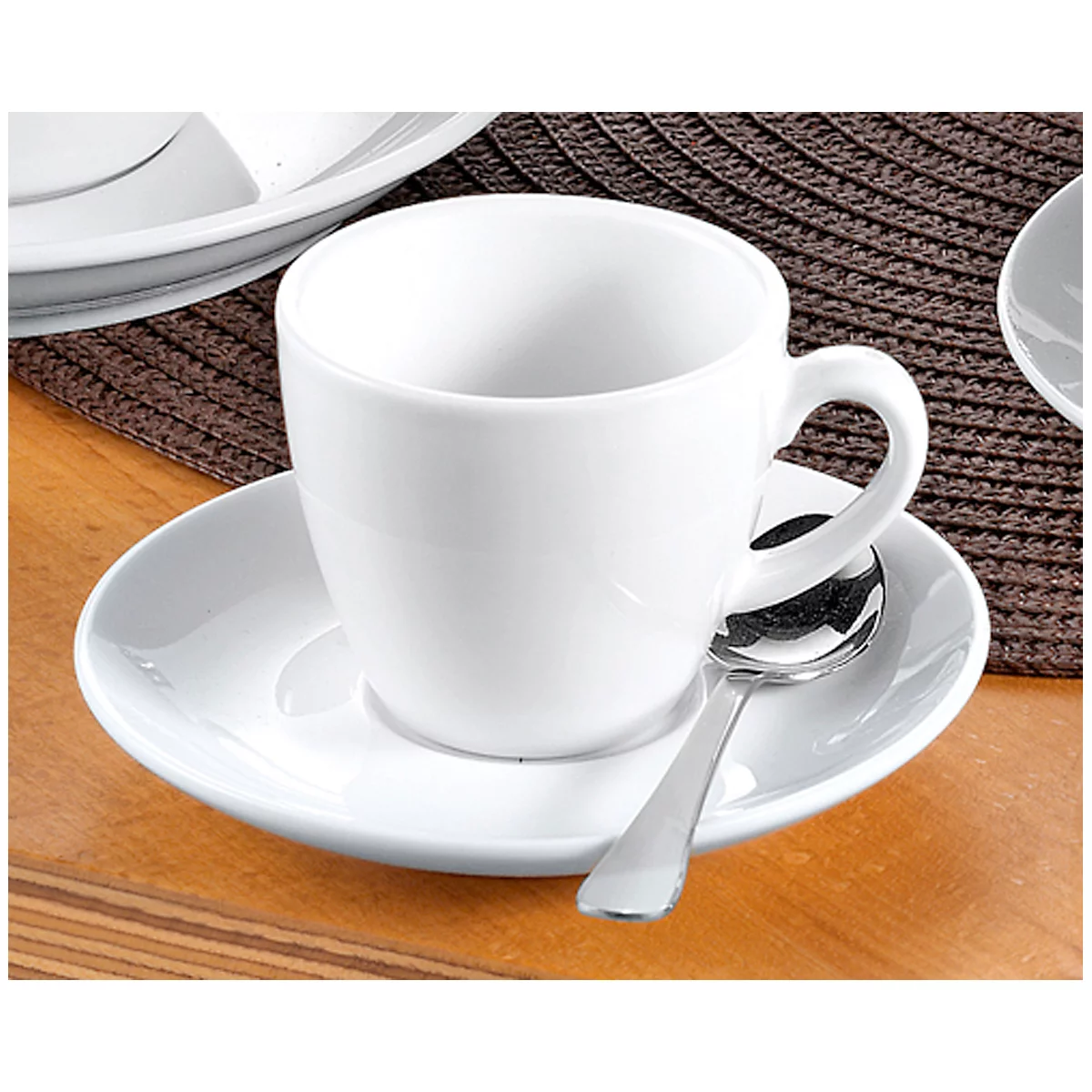 White coffee cup with saucer and spoon, on a table.