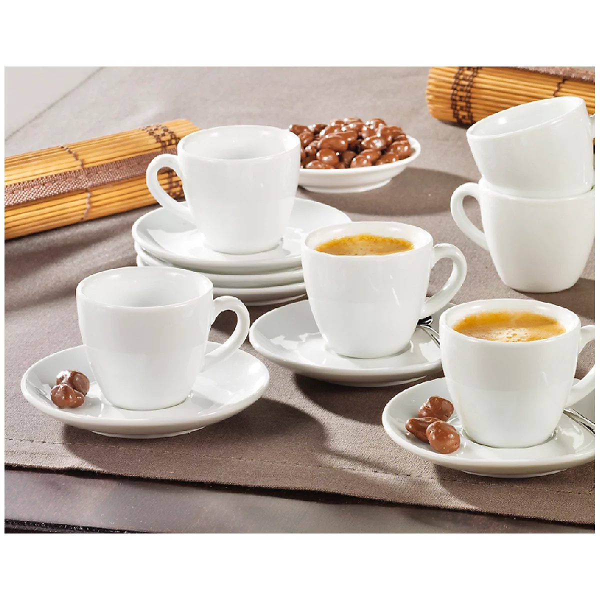 Coffee cup set with saucers, coffee beans and chocolate on a tablecloth.