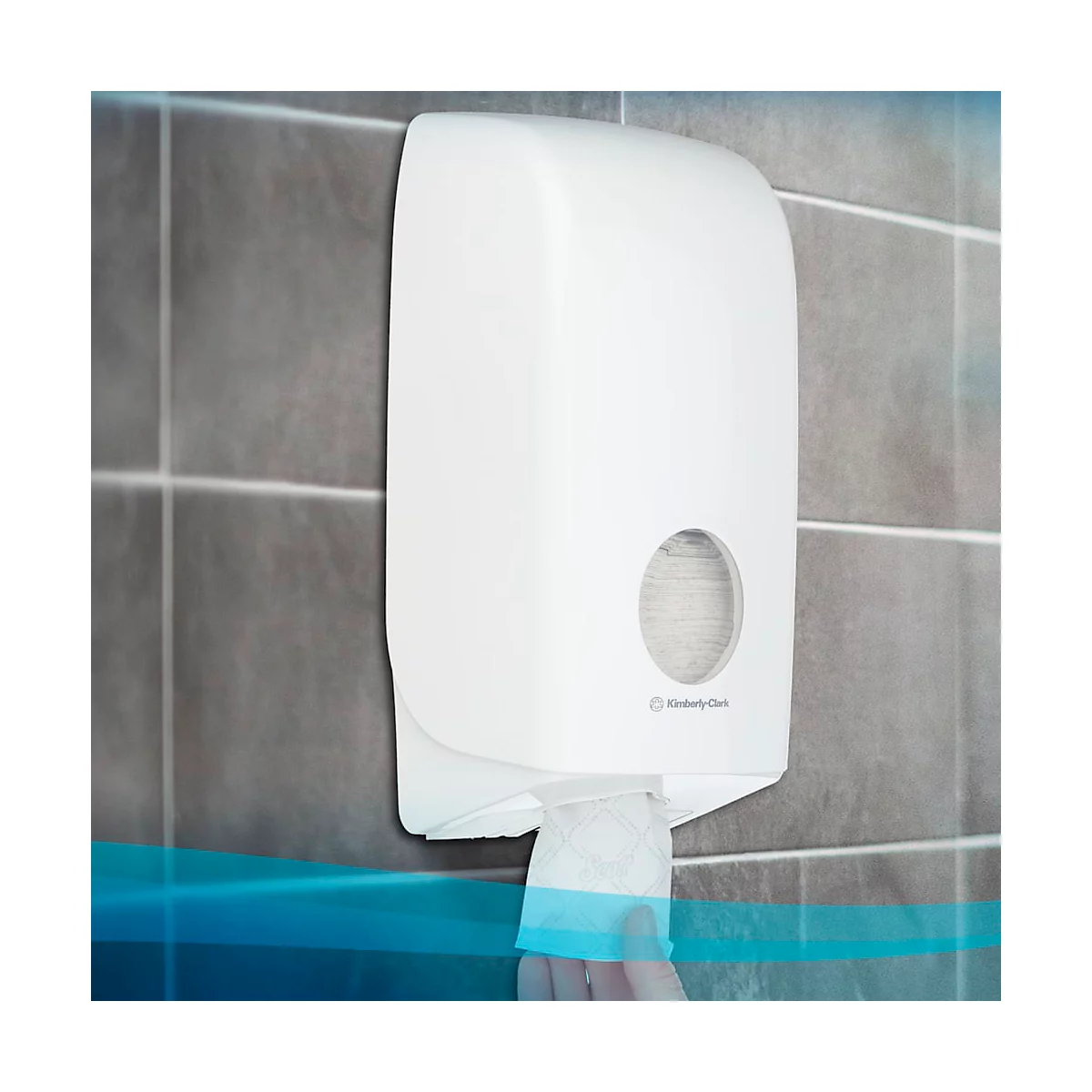 Distributeur d'essuie-mains en papier blanc sur un mur gris. Une feuille est en train d'être retirée.