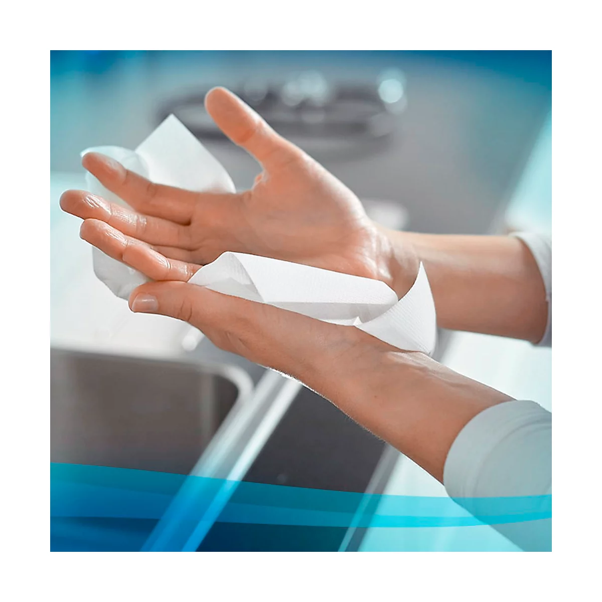 Les mains s'essuient avec une lingette blanche. Environnement lumineux avec un évier en arrière-plan.