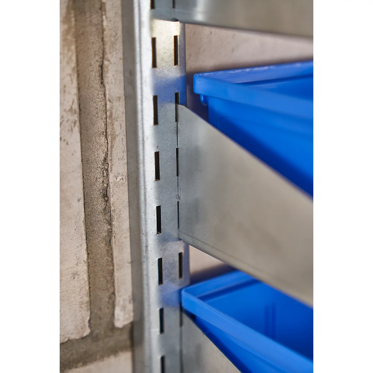 Primer plano de un sistema de estanterías. Estantes metálicos con recipientes de plástico azul.