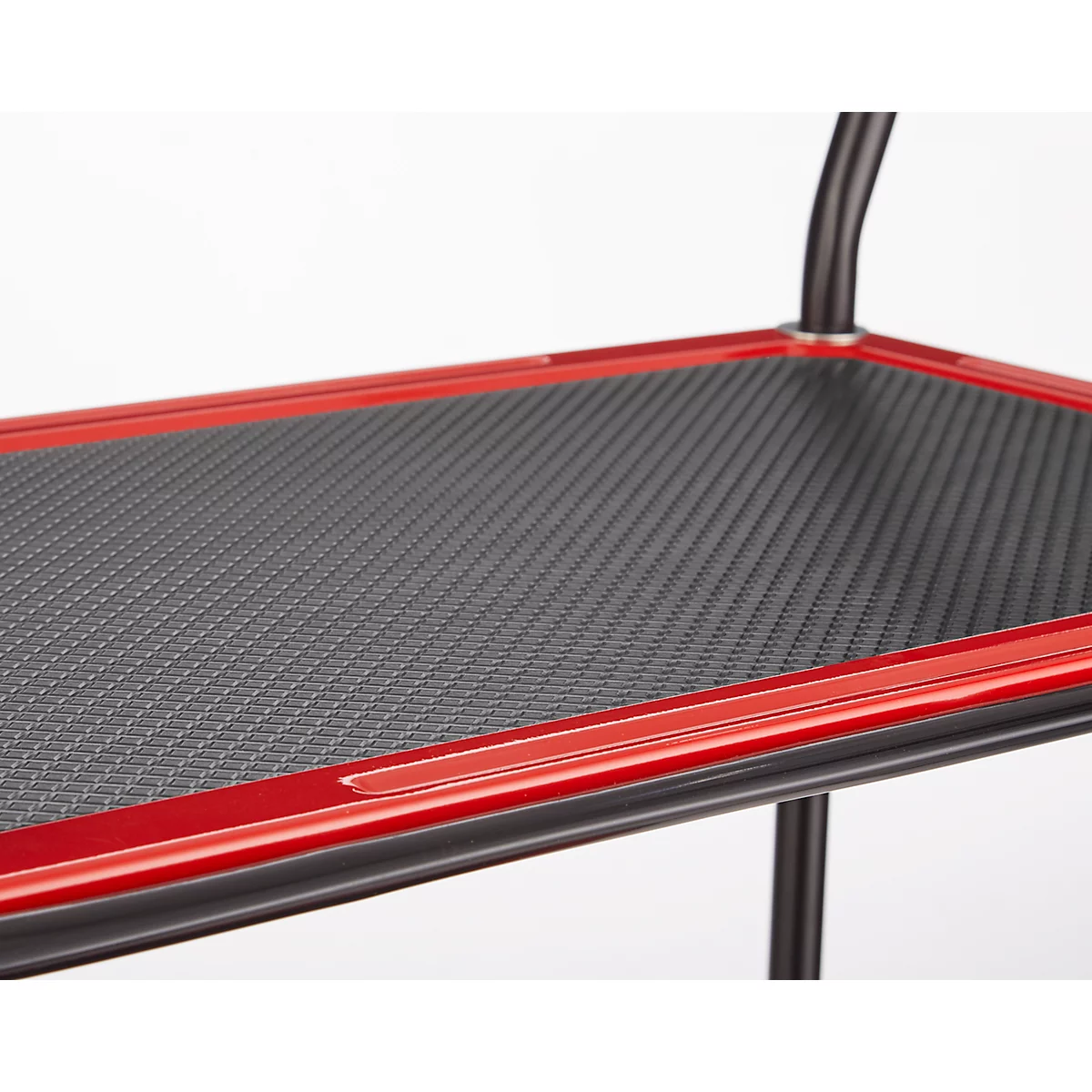 Close-up van een rode en zwarte plank met een gestructureerd patroon. De randen zijn rood en het oppervlak is zwart.