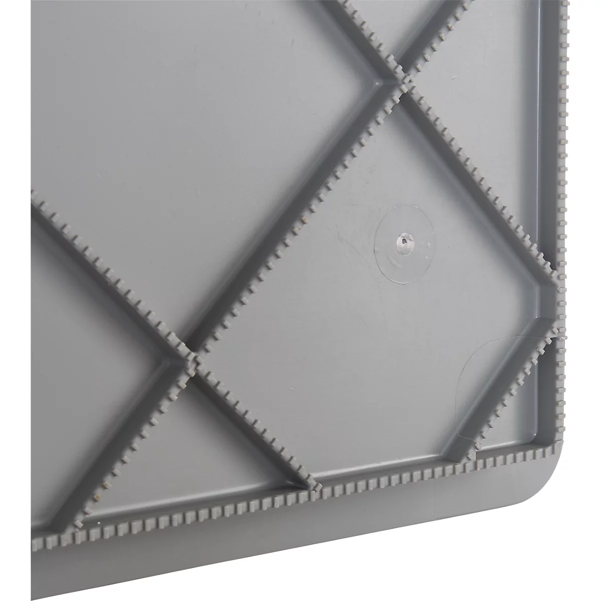 Surface en plastique gris avec des motifs en losange en relief, entourée d'un bord dentelé.