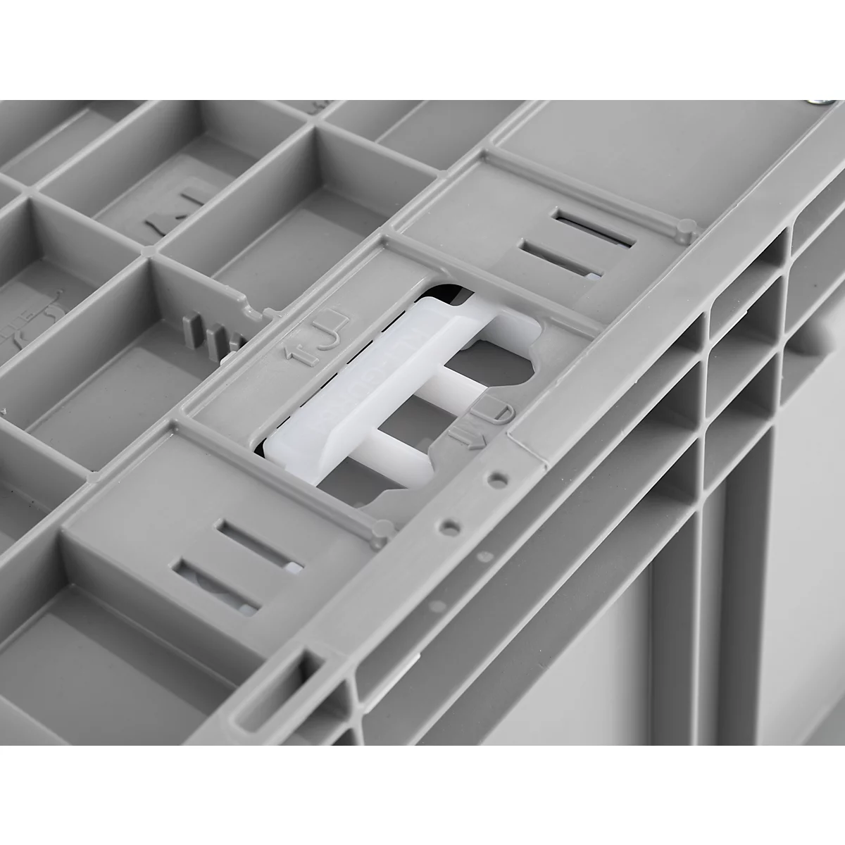 Detailopname van een grijze plastic doos met een witte handgreep. De handgreep is bevestigd in een uitsparing.