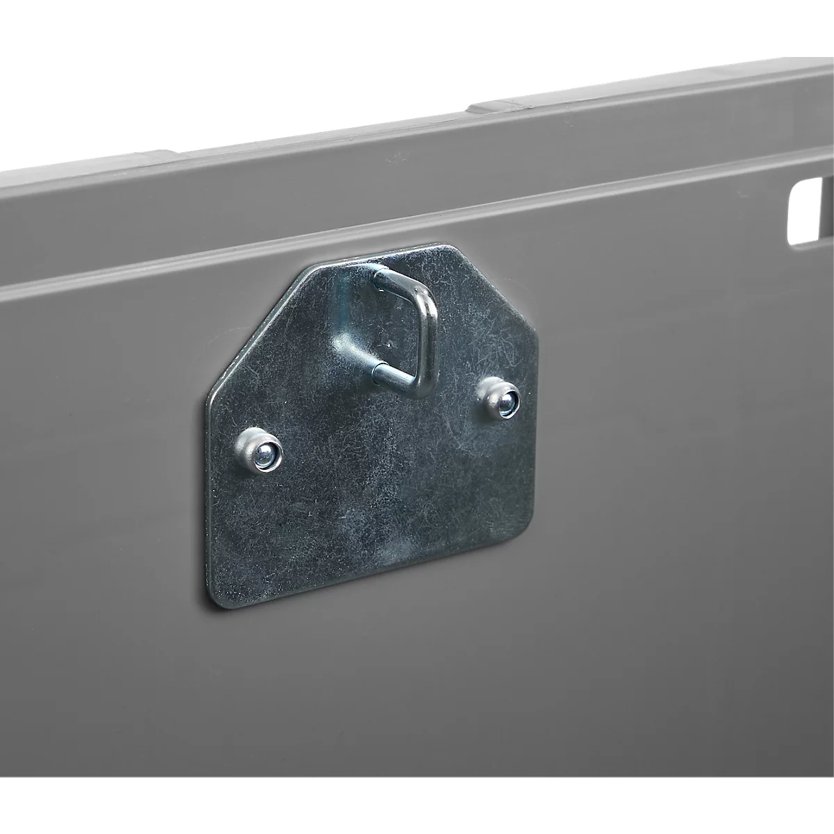 Detailaufnahme eines Metallhakens, der an einer grauen Oberfläche befestigt ist. Der Haken ist Teil einer größeren Struktur.