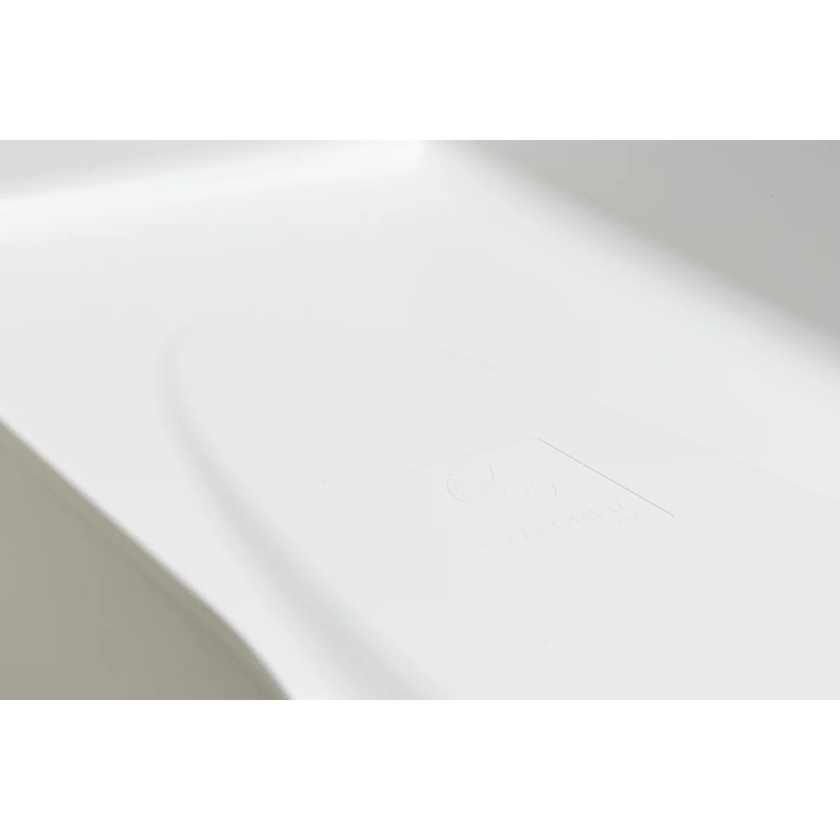 Detailopname van een wit, afgerond object met een gevormde markering. Het object heeft een glad oppervlak.