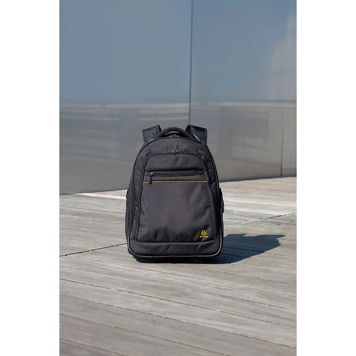 Schwarzer Rucksack vor grauem Hintergrund, Blick von vorne, braune Reißverschlüsse.
