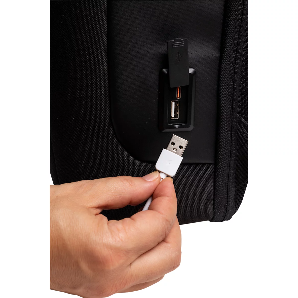 Nahaufnahme: Hand steckt weißen USB-Stecker in schwarzen Rucksack. USB-Anschluss.