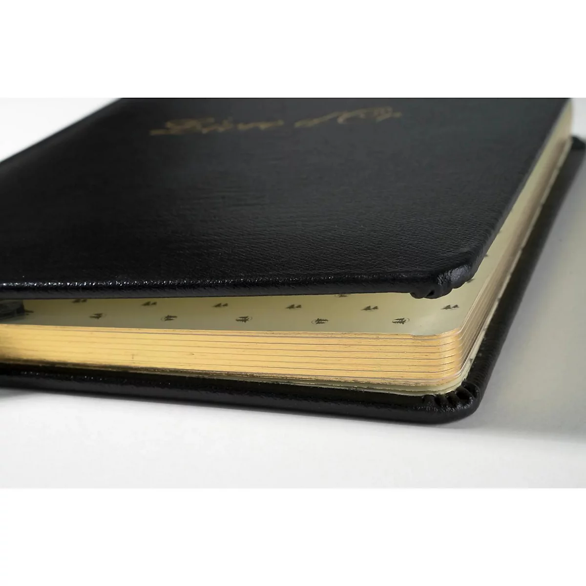 Nahaufnahme eines schwarzen Buches mit goldenen Seiten. Der Buchdeckel ist leicht geöffnet und zeigt bedruckte Seiten.