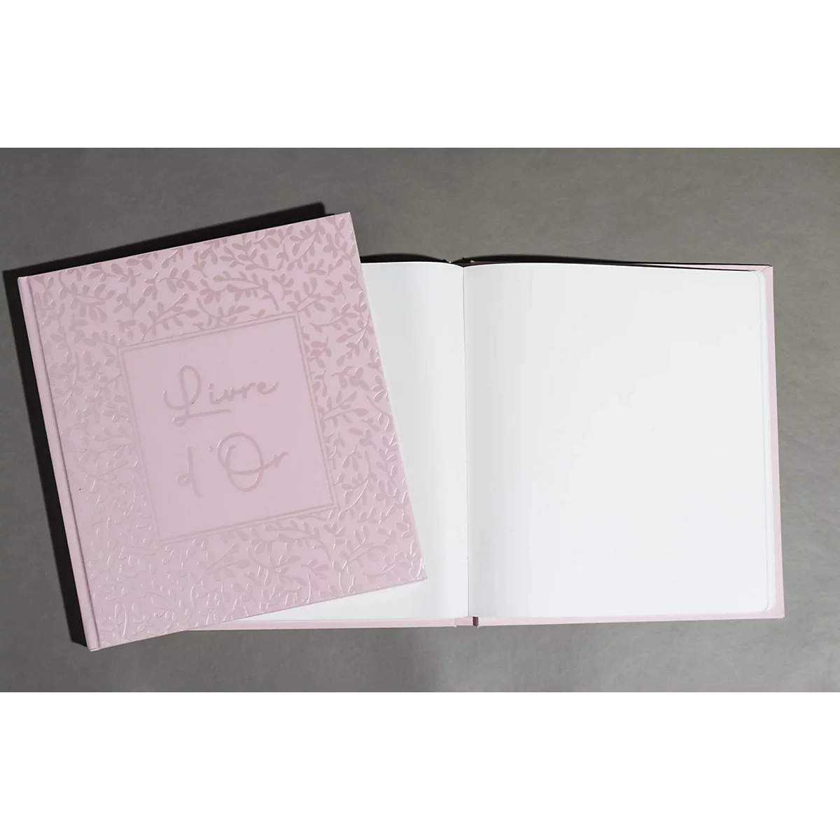 Hellrosa Buch mit floralem Muster und Schriftzug 'Livre d'Or'. Das Buch ist aufgeschlagen und zeigt leere, weiße Seiten.