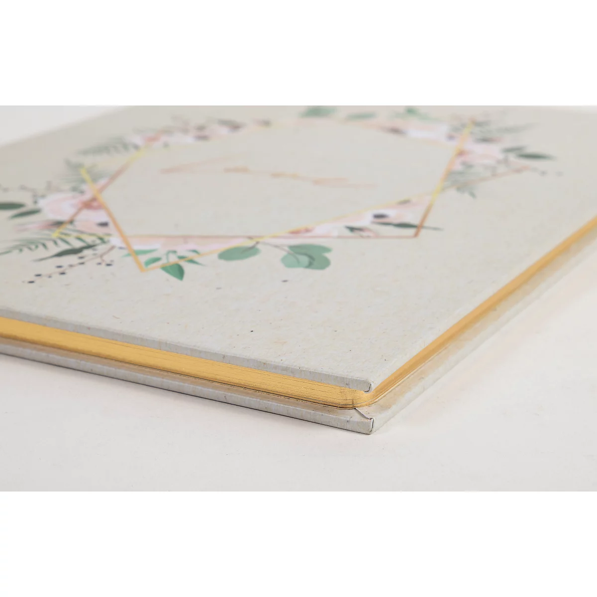Un livre de couleur claire avec un motif floral et des accents dorés, photographié légèrement d'en haut.