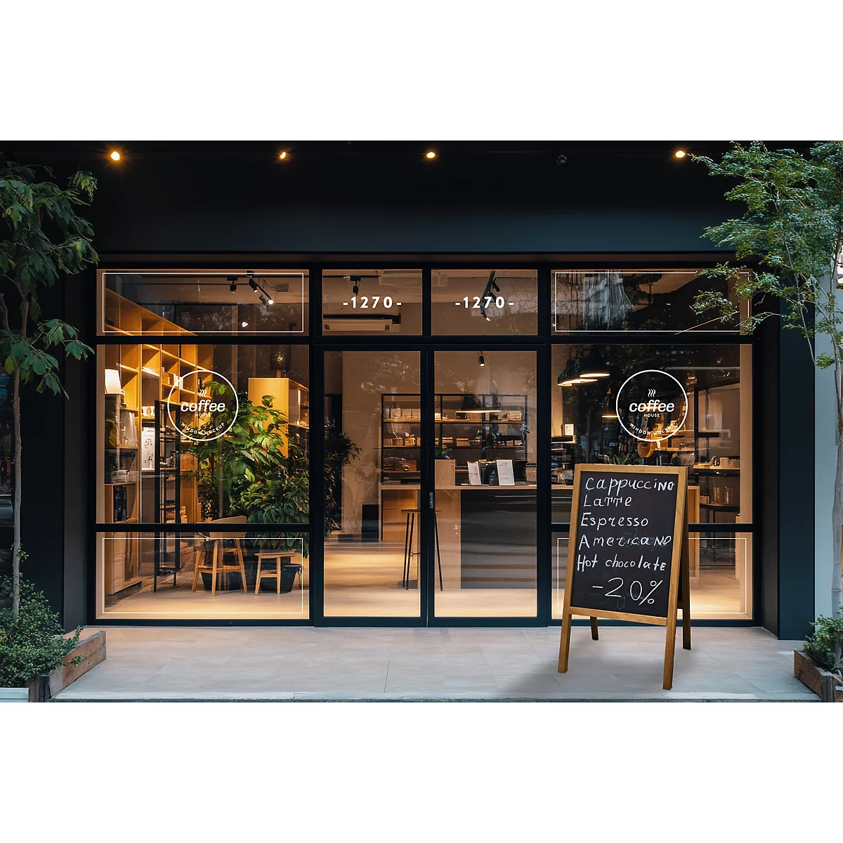 Un café avec de grandes baies vitrées, une enseigne et des plantes. L'éclairage intérieur, un comptoir et des étagères sont visibles.