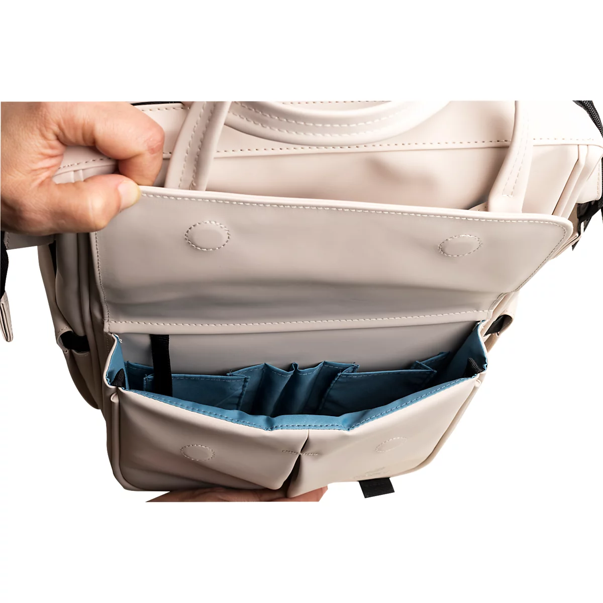 Beigefarbene Handtasche, offene Klappe mit blauem Innenfutter. Hand greift hinein.