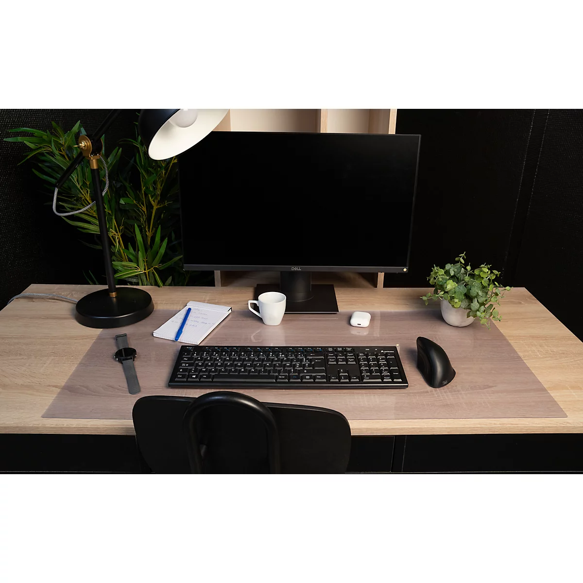 Büroarbeitsplatz mit Monitor, Tastatur, Maus, Tischlampe, Notizblock und Kaffeetasse. Holzoberfläche mit transparentem Schutz.