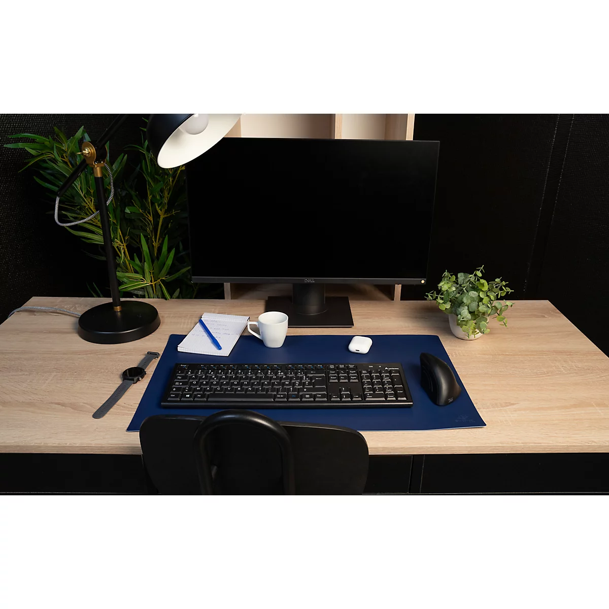 Schreibtisch mit Monitor, Tastatur, Maus, Kaffeetasse, Notizblock und Pflanze.