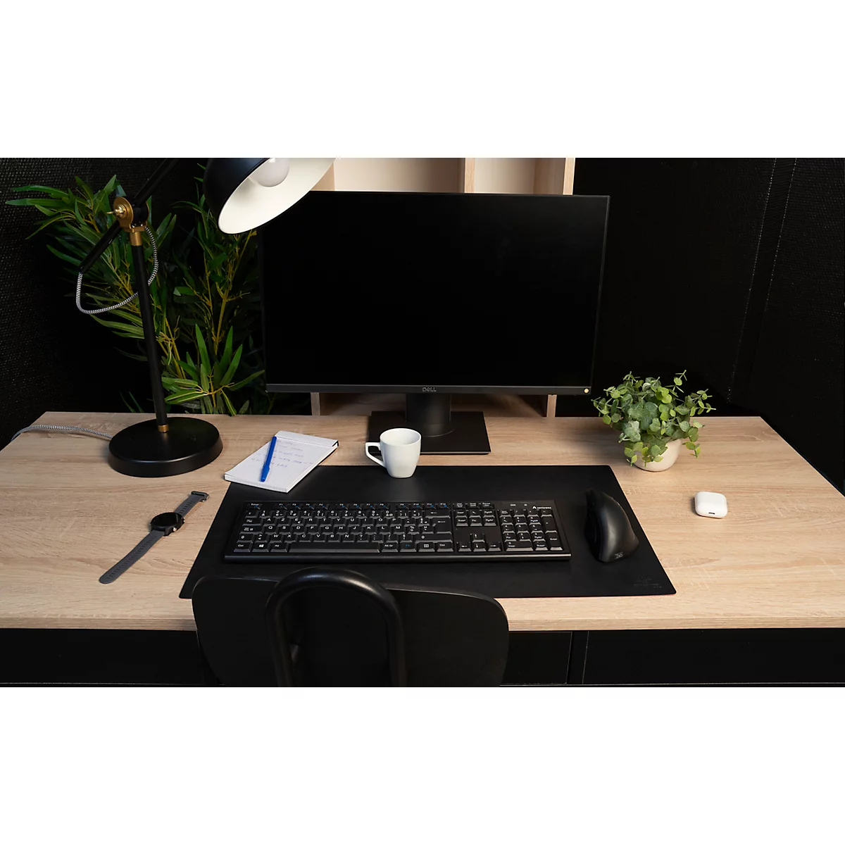 Ein Schreibtisch mit Computer, Tastatur, Maus, Tasse, Pflanze, Notizblock und Armbanduhr.