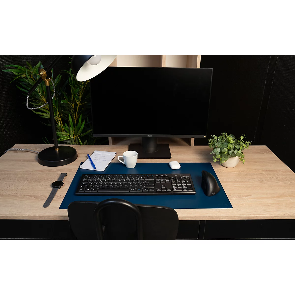 Büroarbeitsplatz mit Schreibtisch, Monitor, Tastatur, Maus, Lampe, Uhr und Pflanze.