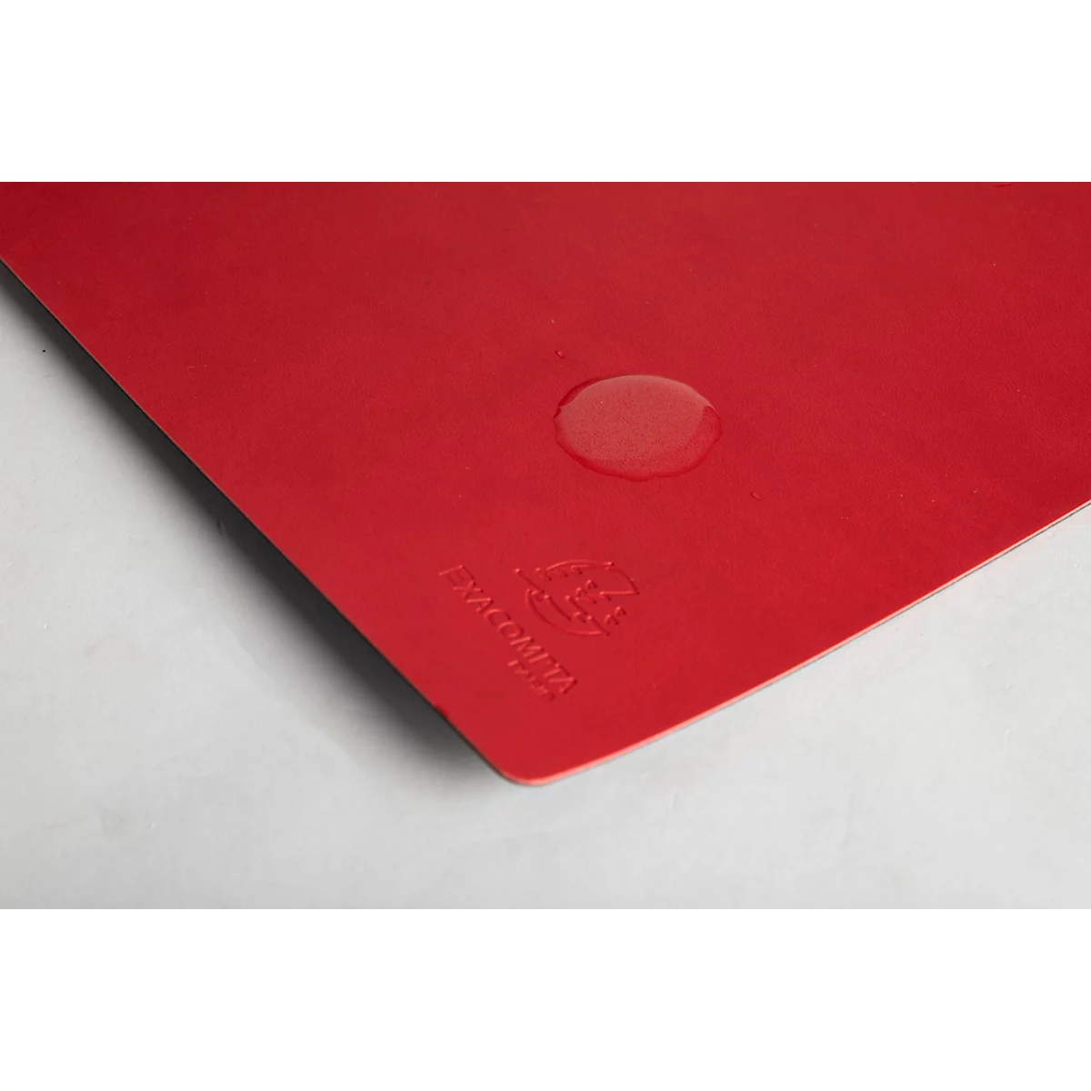 Gros plan d'un plateau rouge avec une goutte d'eau. Le nom de la marque est visible en bas à gauche.