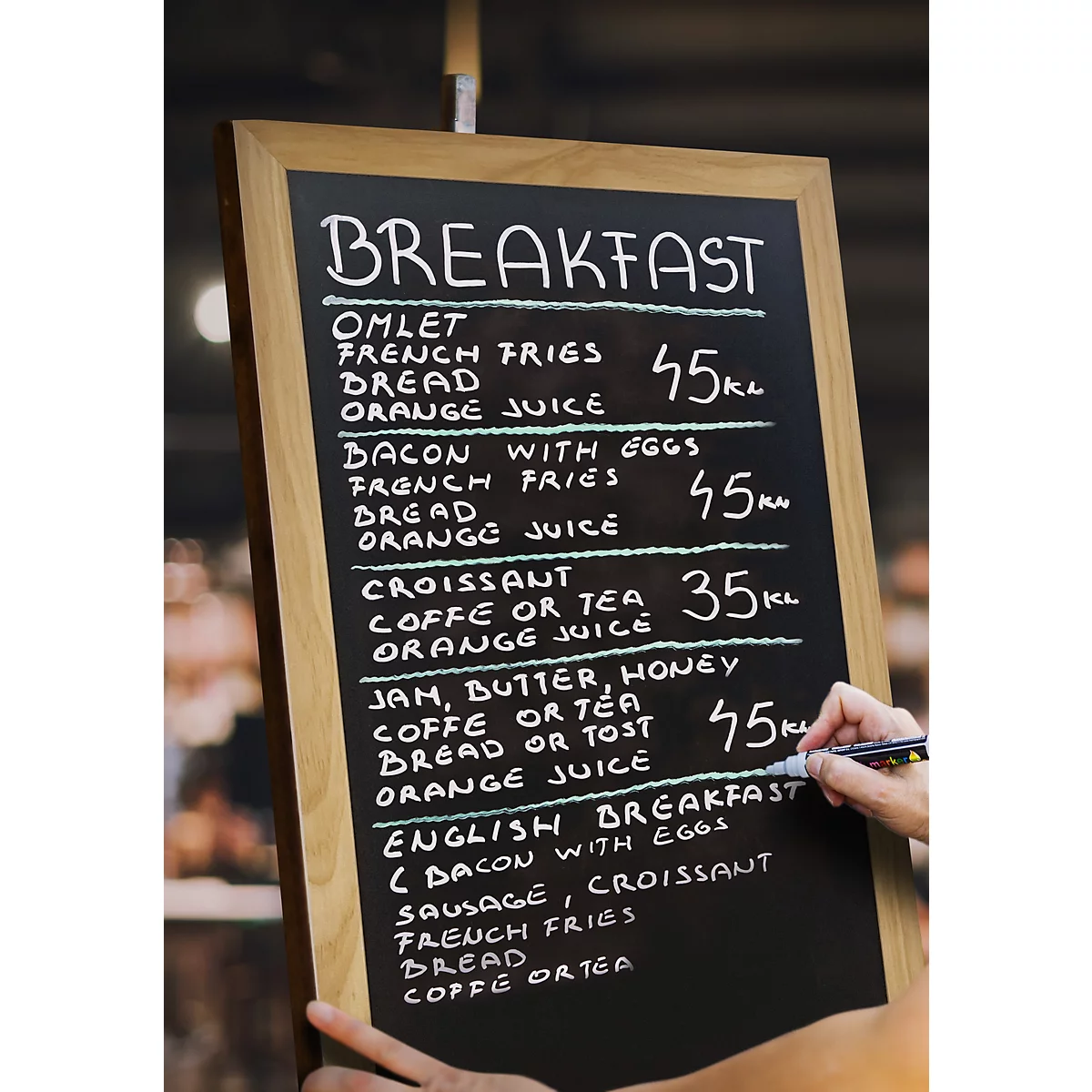 Un menu de petit-déjeuner manuscrit dans un café. Le tableau noir énumère diverses options de petit-déjeuner avec les prix.