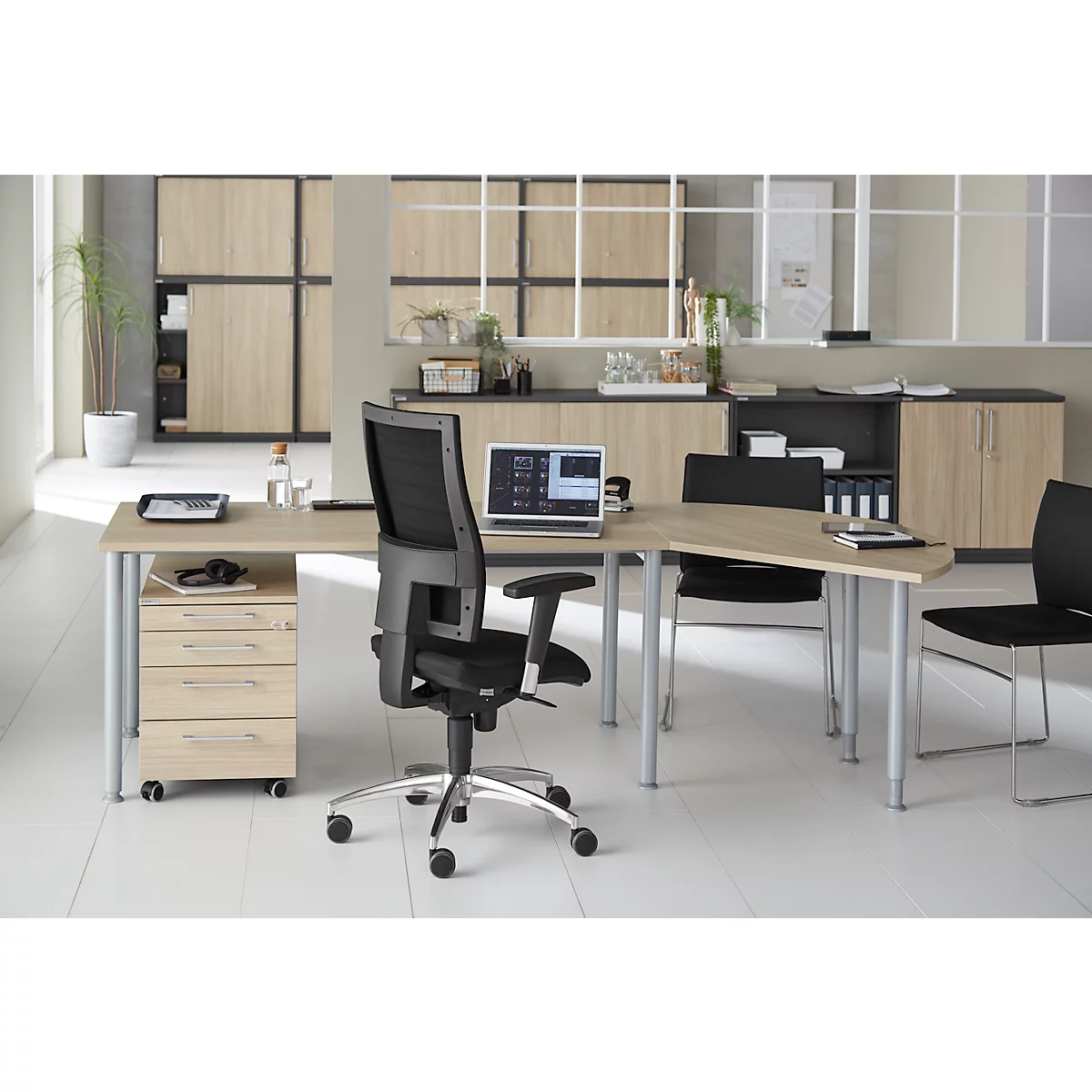 A modern office with a desk, chairs and cabinets. A laptop sits on the desk.