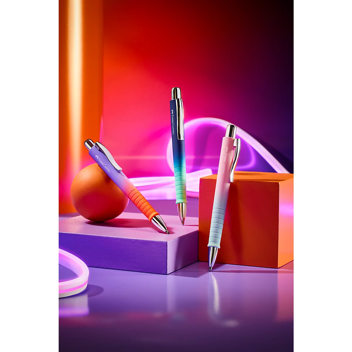 Drei bunte Kugelschreiber mit Farbverlauf auf geometrischen Blöcken vor leuchtendem, neonfarbenem Hintergrund.