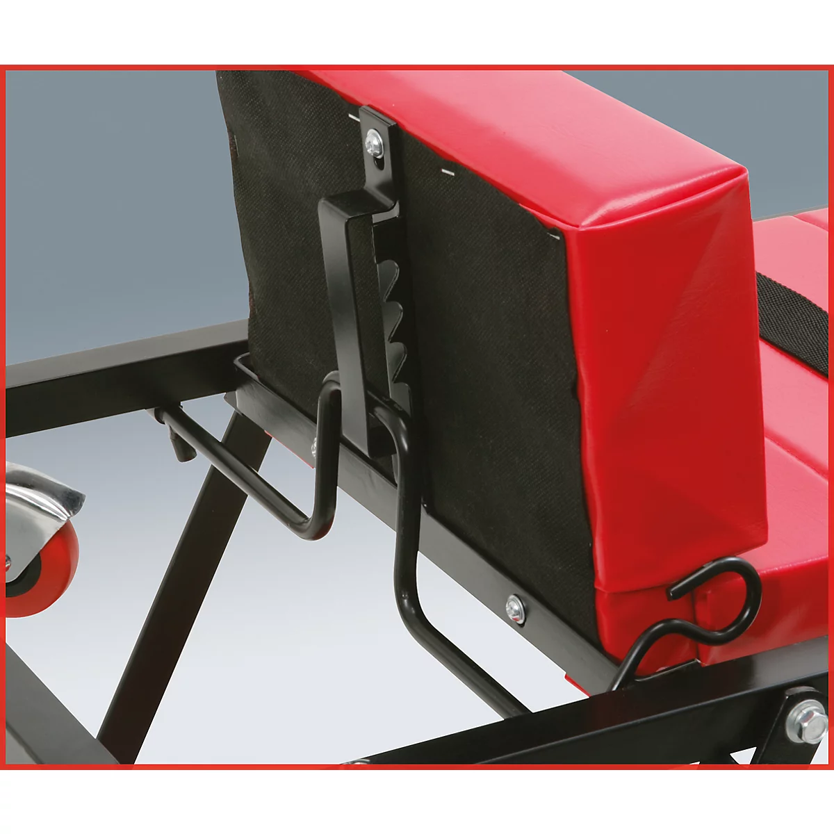 Detailaufnahme eines roten Stuhls mit schwarzem Metallgestell. Der Fokus liegt auf dem Mechanismus zur Rückenlehnenverstellung.