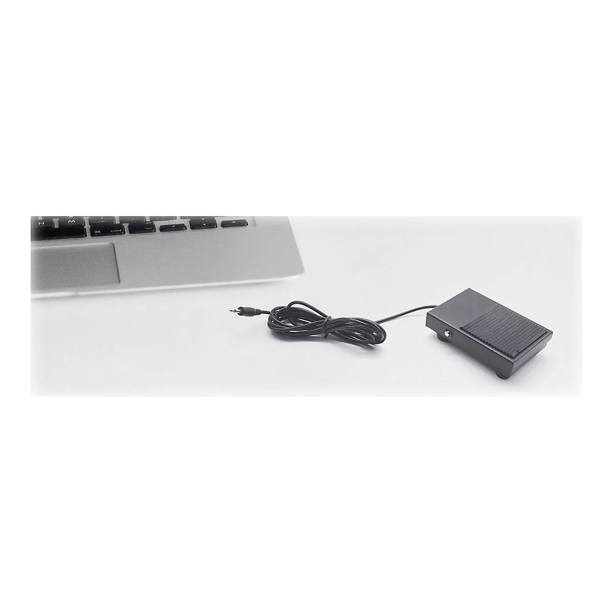 Ein schwarzes FuÃŸpedal mit Kabel liegt neben einem Laptop.