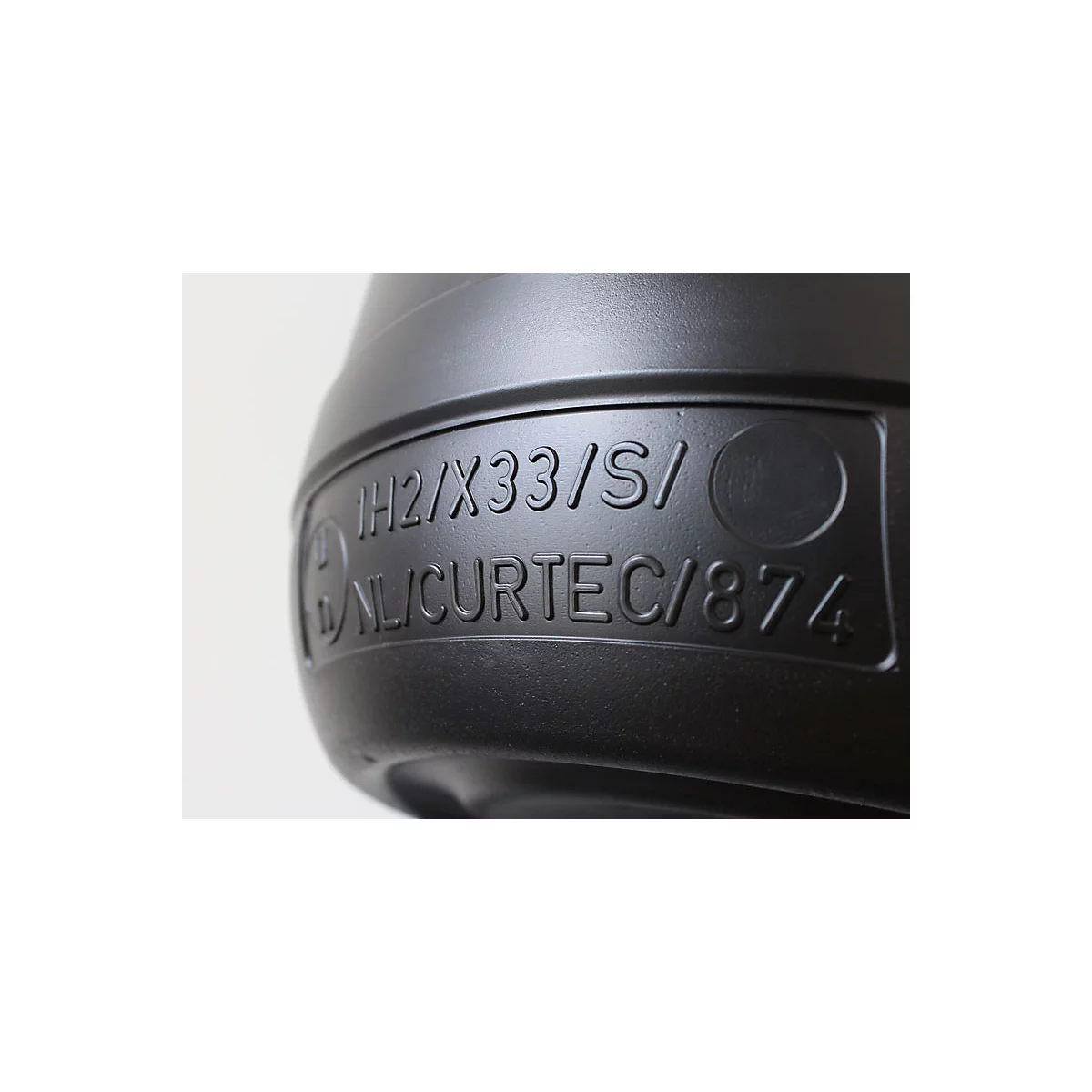 Nahaufnahme eines schwarzen Kunststoffbehälters mit eingravierter Schrift: IH2/X33/S/ NL/CURTEC/874.