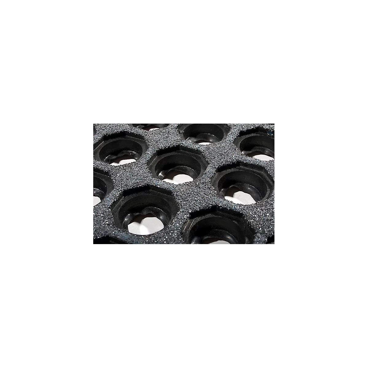 Close-up of a gray, hexagonal honeycomb structure. Black, circular recesses are in the honeycomb.