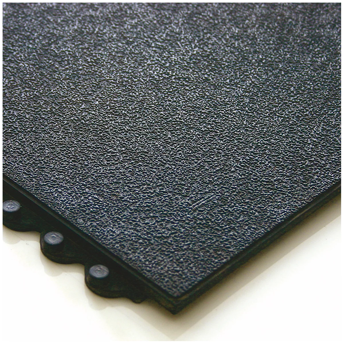 Close-up of a black rubber floor tile with textured surface and connector pins on the edges.