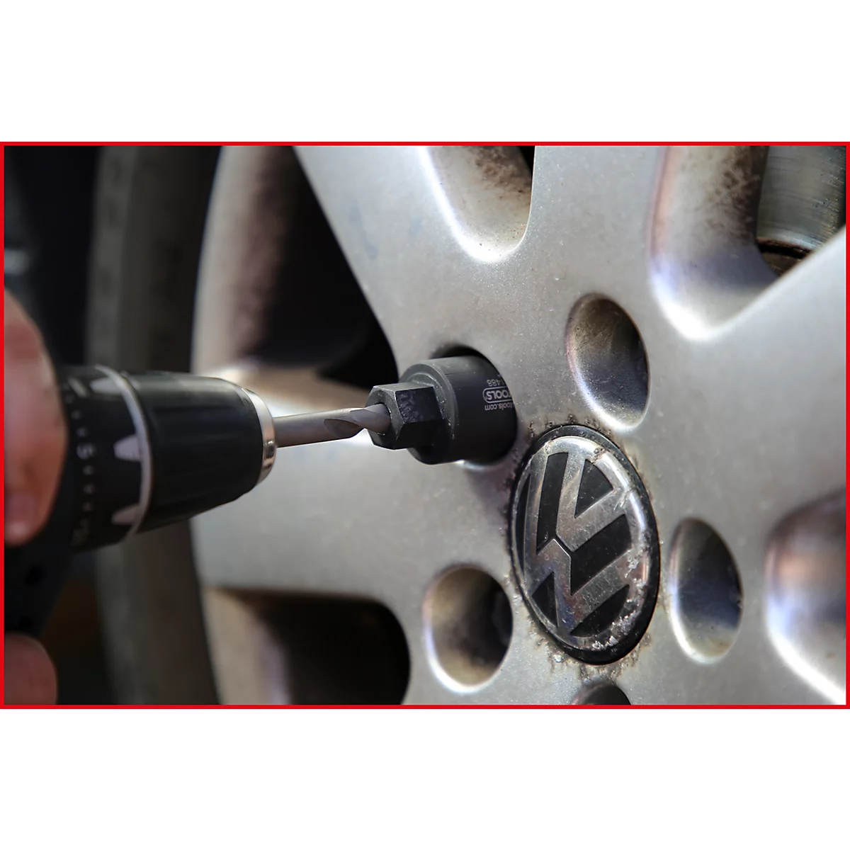Nahaufnahme einer Person, die mit einem Akkuschrauber eine Radmutter an einem VW-Rad löst.