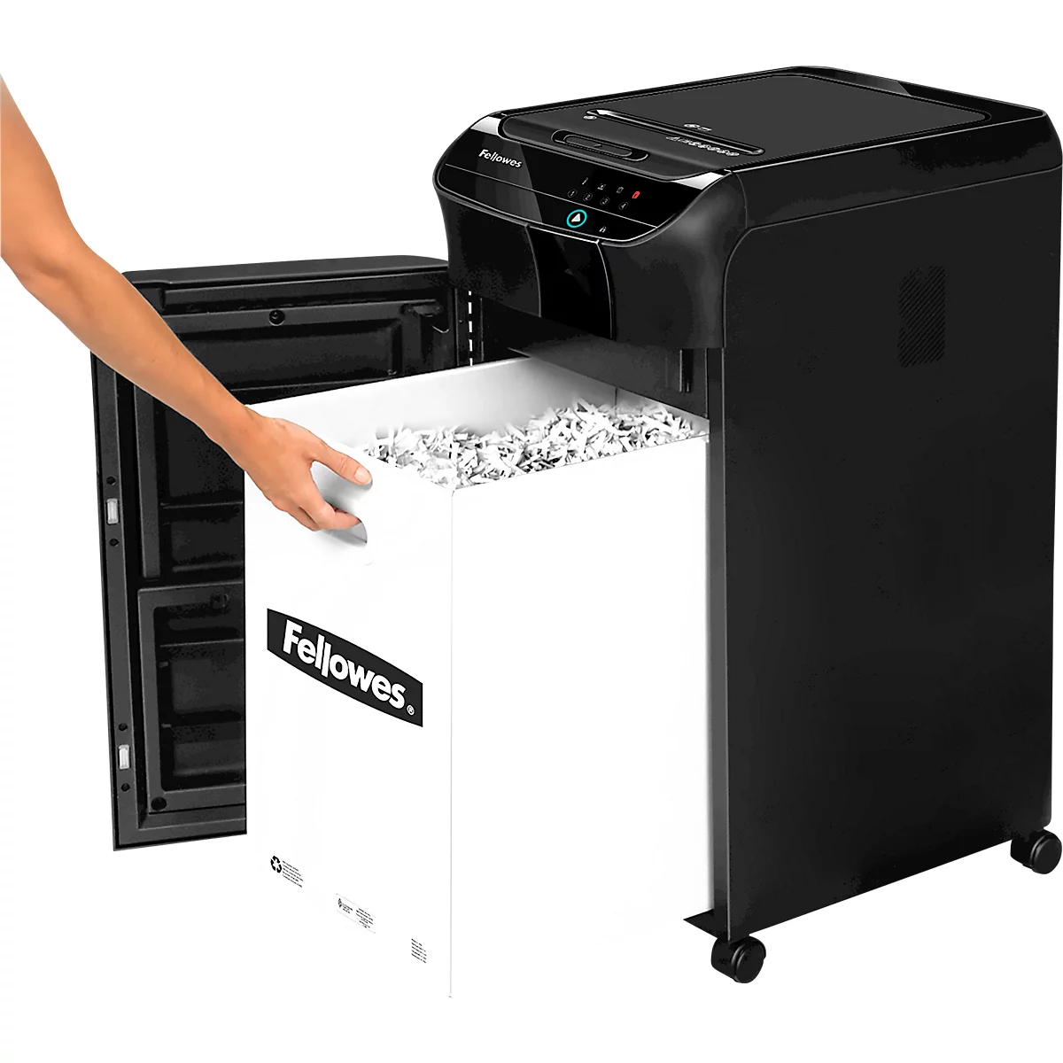 A person empties a paper shredder. A white container of shredded paper is being removed. The device is black and has wheels.