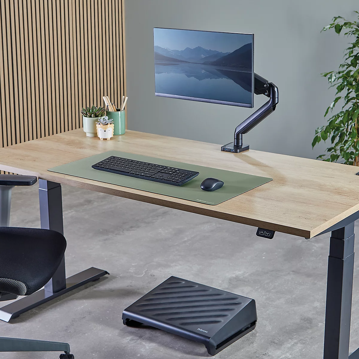 Open notebook with pen, laptop stand and plant on desk.